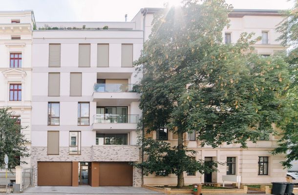 Neues modernes Wohngebäude zwischen traditionellen Altbauten in städtischer Umgebung.