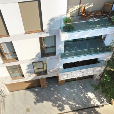 Modernes Wohngebäude mit Glasbalkonen, stilvoller Fassade und grüner Umgebung für urbanes und komfortables Wohnen.